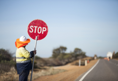 A man with a stop sign on the side of a road in Upskills QLD.