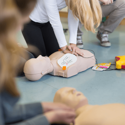 A group of people practicing Cardiopulmonary Resuscitation around a dummy.