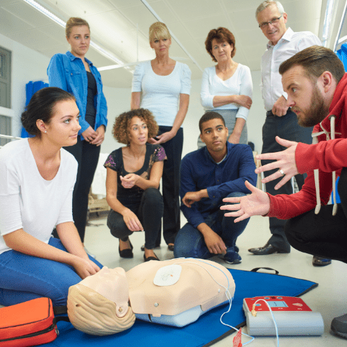 A group of people performing First Aid around a dummy.
