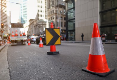 A Traffic Controlled city street with construction signs and traffic cones.