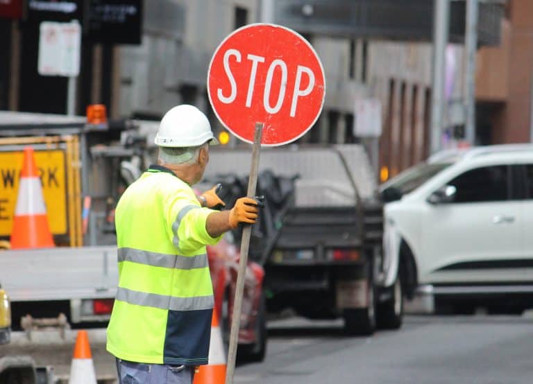 Construction worker controlling traffic near active roadway.