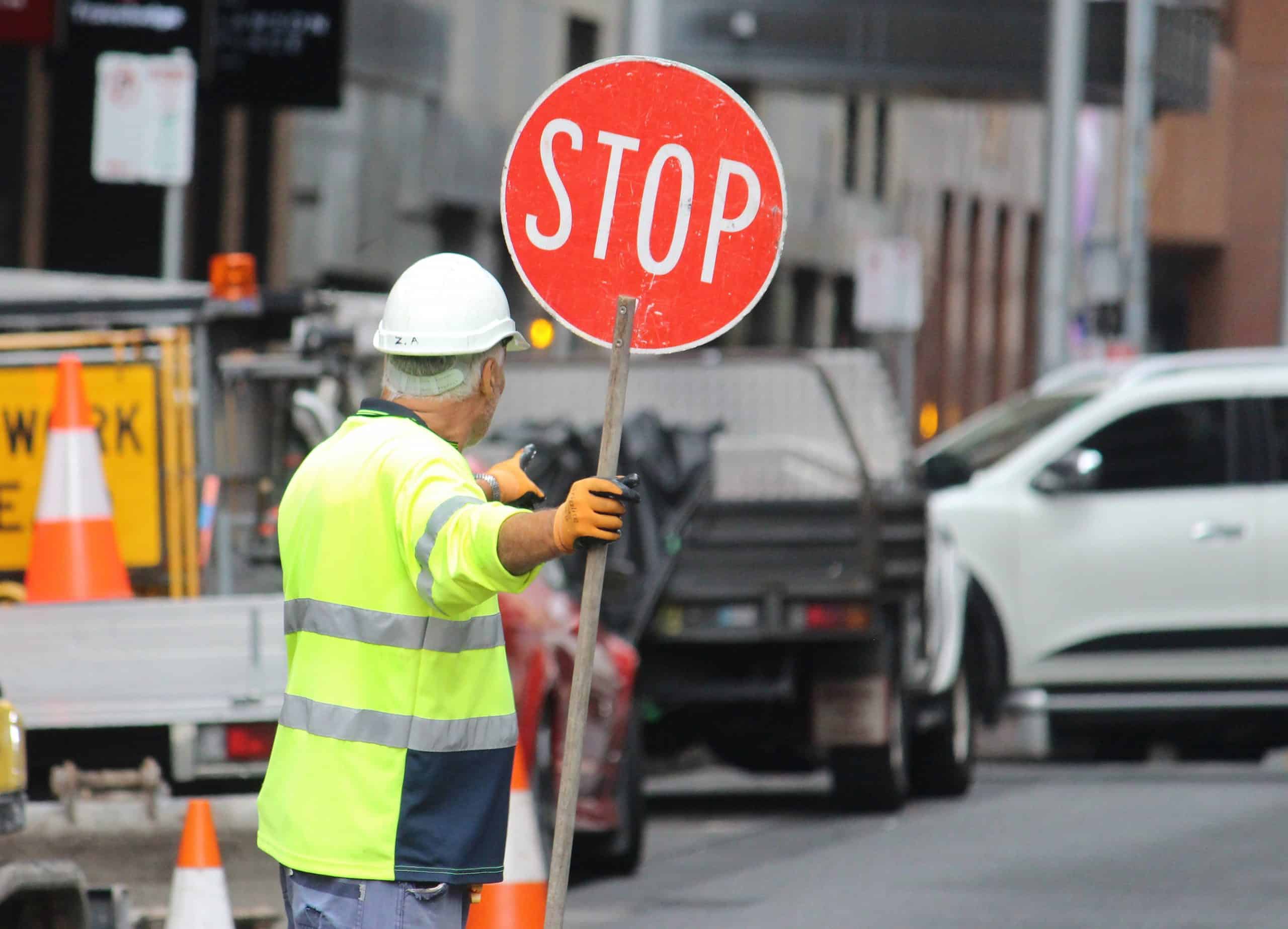 A construction worker controlling traffic on a city street with a stop sign from the Traffic Management Bundle.