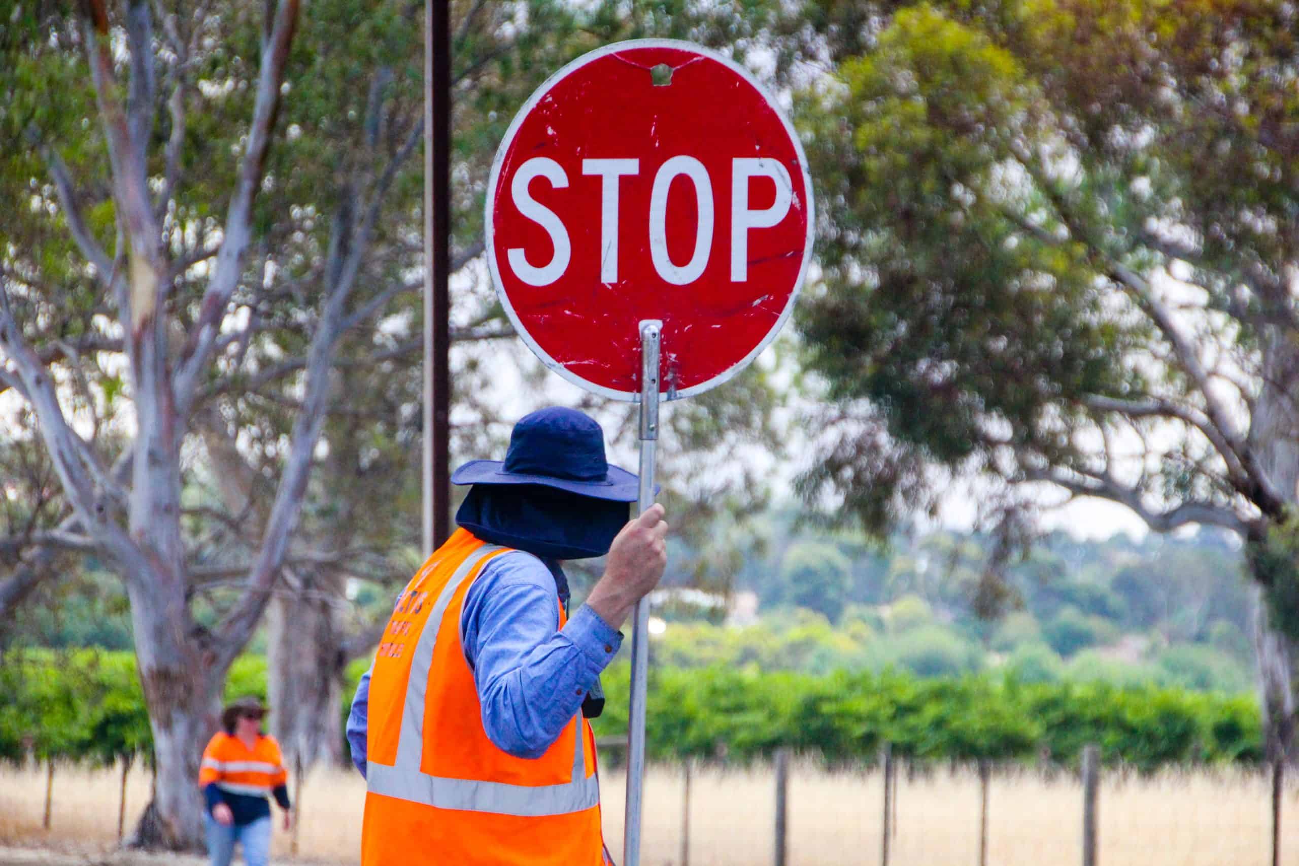 A man holding a stop sign in a safety vest.