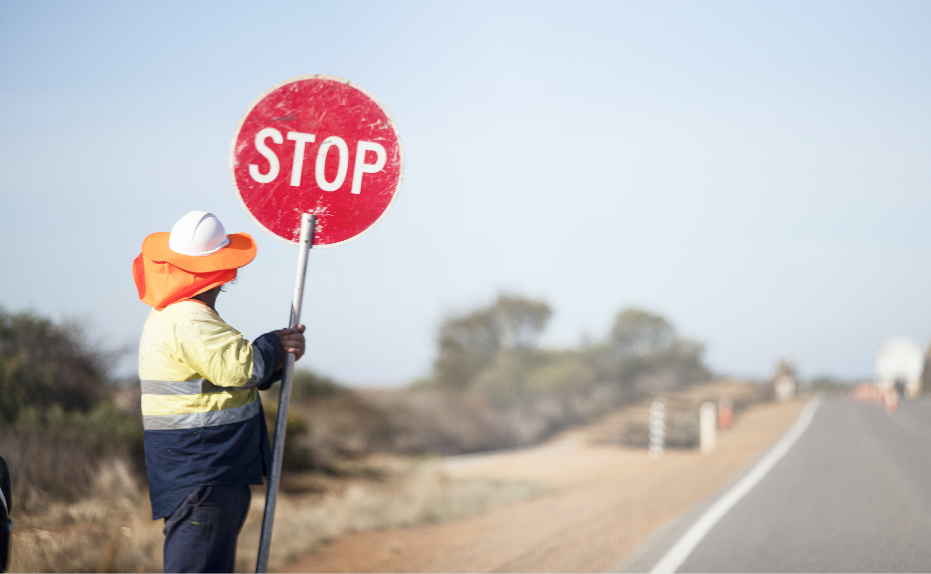 a man holding a stop sign on the side of the road.