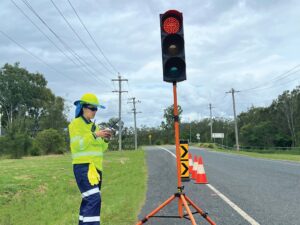 Traffic controller in high-visibility clothing operating light.