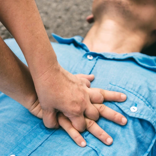 Hands performing chest compressions during CPR/first aid training on an adult lying on the ground