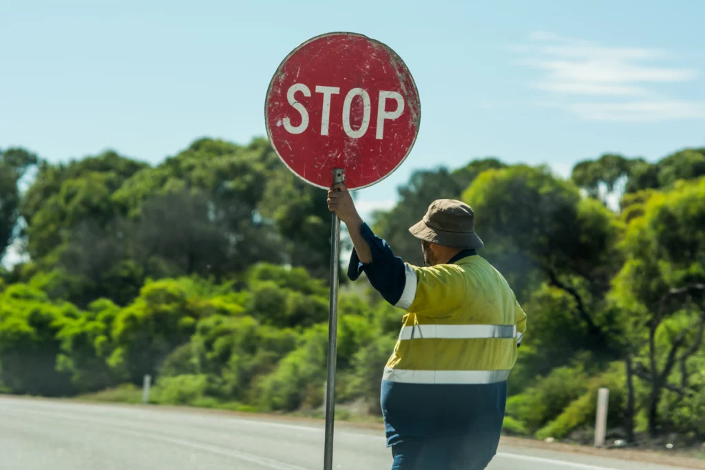 Traffic Controller in holding a STOP sign while managing traffic at a roadwork site in Rockhampton, demonstrating safe traffic control practices during road construction in Queensland.
